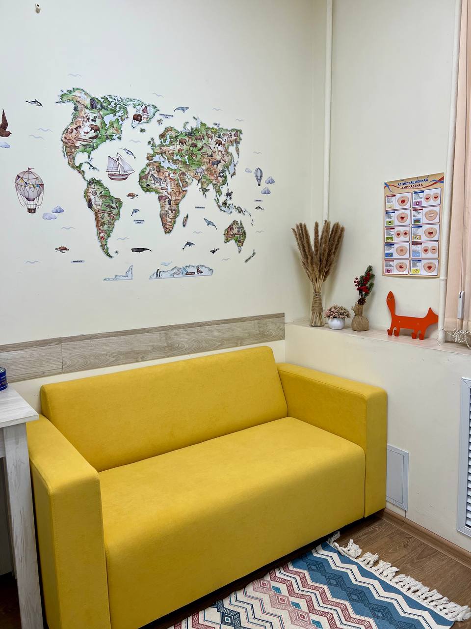 Зона ожидания — уютный жёлтый диван и карта мира на стене